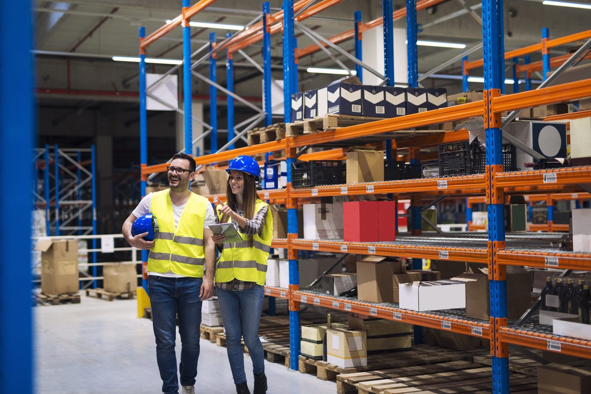Equipo de almacén recorriendo el pasillo entre racks de mercancía